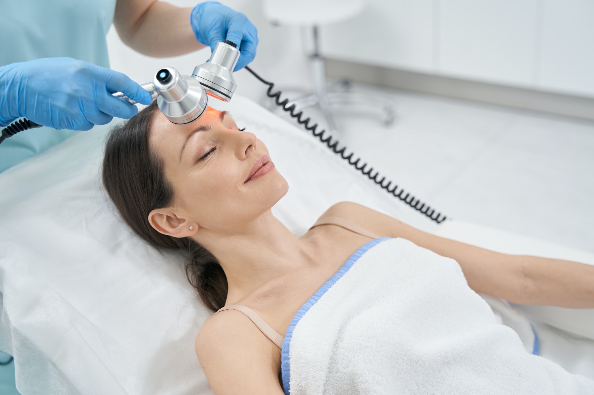 Woman receiving radiofrequency facial treatment in clinic